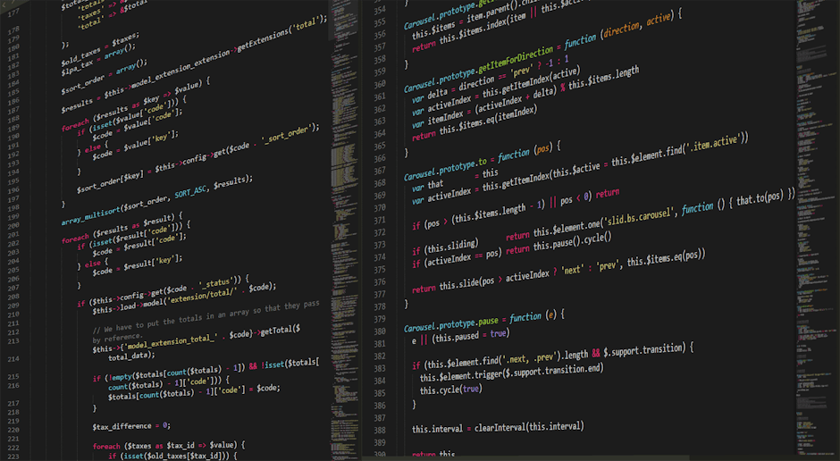 A high-resolution digital photograph captures a close-up view of a computer screen displaying lines of colourful code on a dark background. The code appears to be JavaScript or similar programming lan